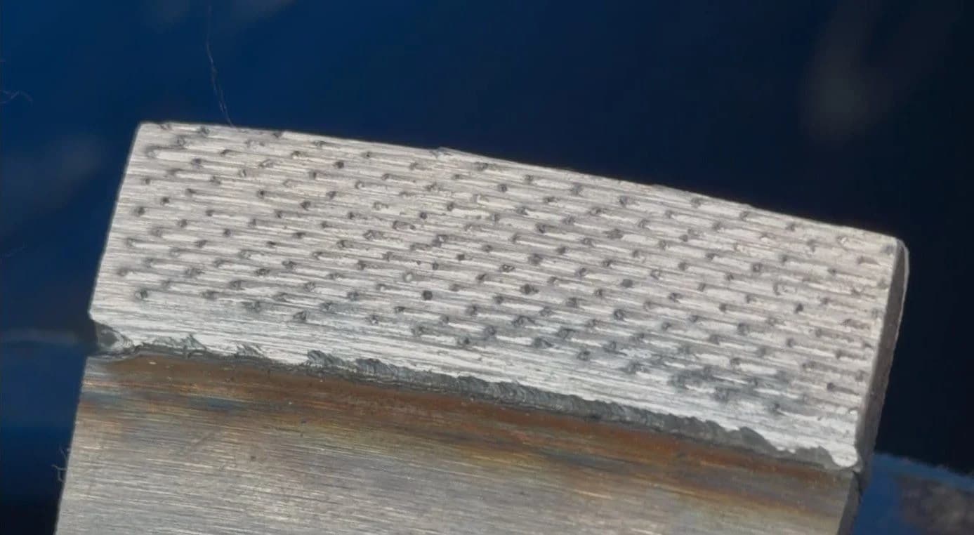 Close-up of an Exakt segment welded to a blade rim, with the diamonds standing proud of the metal.