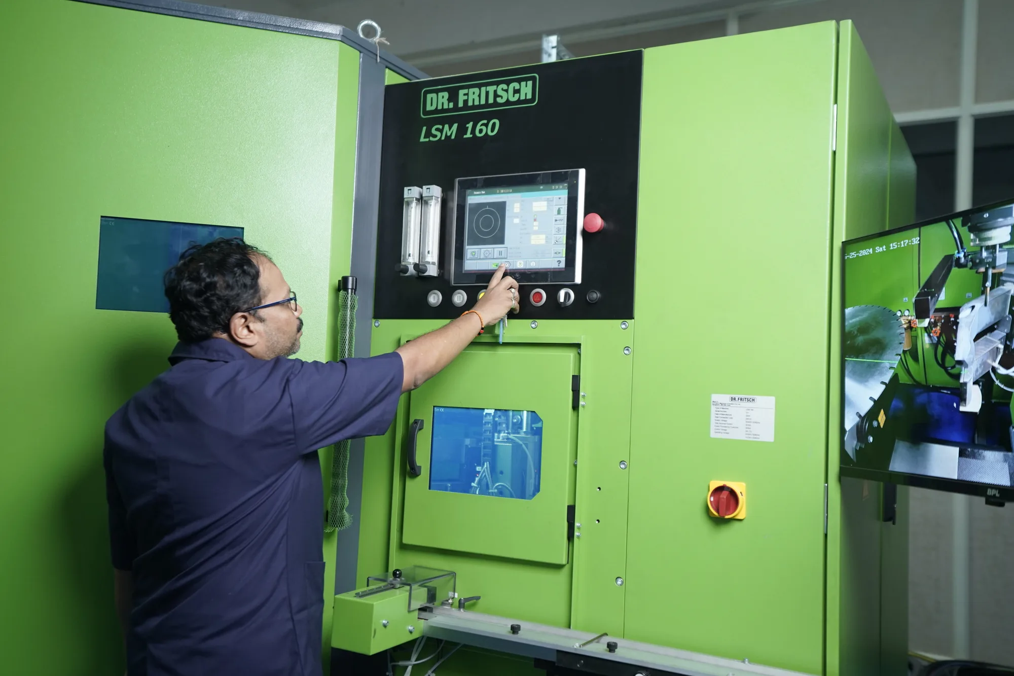 An operator at the touchscreen of a green Dr Fritsch LSM 160 laser welding machine, the nameplate legible above the panel.