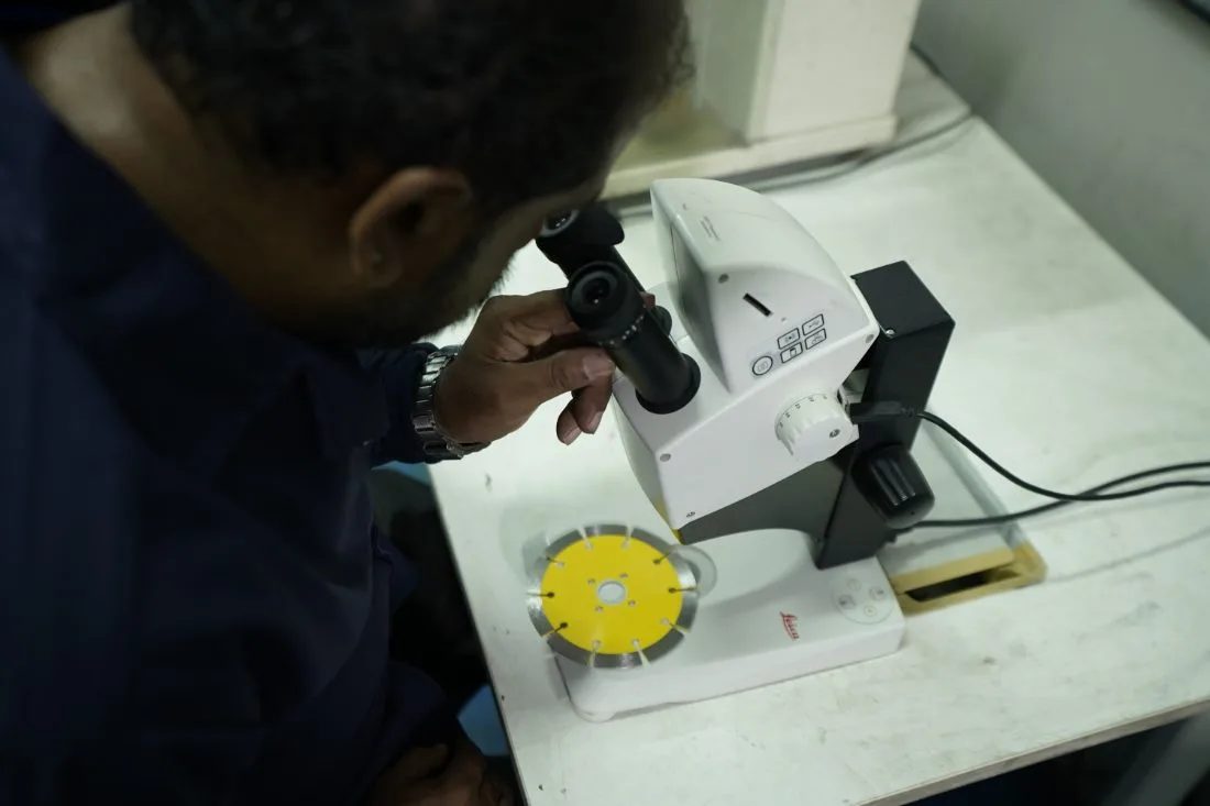 Technician inspecting a diamond blade segment under a microscope